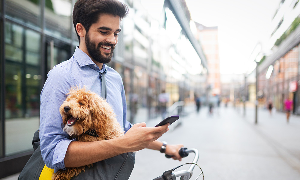 A man looks at his phone while holding a puppy.